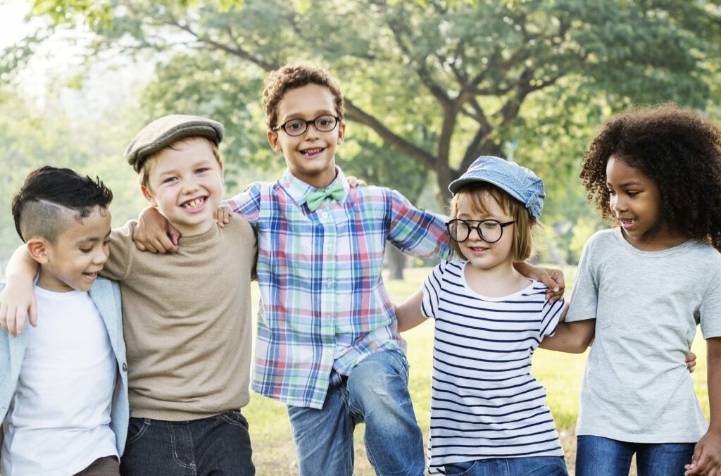 Group of young kids smiling with their arms around each other, representing happy and healthy dental care experiences at Kids Smiles Pediatric Dentistry.
